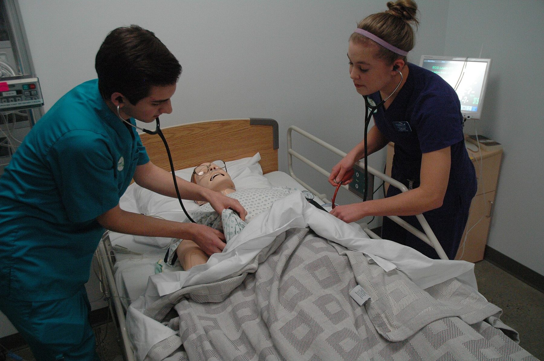 Två studenter tränar ett praktiskt moment vid en patientsimulator i metodrum.