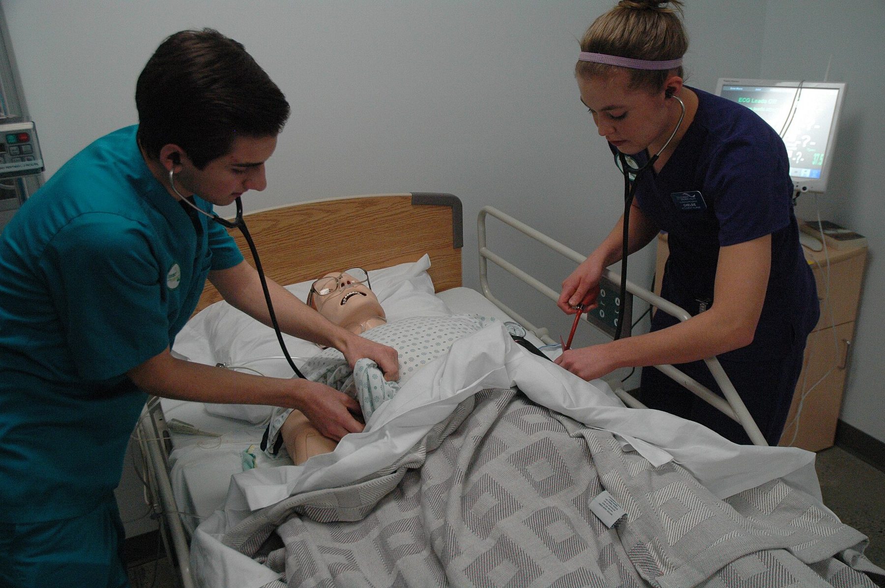 Två studenter arbetar koncentrerat vid en patientsimulator i metodrum.